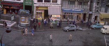 Movie still from “A Woman Is a Woman” (1961), directed by Jean-Luc Godard – A group of people walking down a street; Extreme Wide shot, High angle