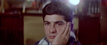 Movie still from “A Woman Is a Woman” (1961), directed by Jean-Luc Godard – A young man is holding his hand to his face; Close Up shot, Low angle