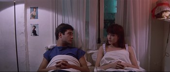 Movie still from “A Woman Is a Woman” (1961), directed by Jean-Luc Godard – A man and a woman sitting in a bed together; Medium shot, High angle