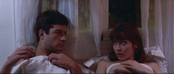 Movie still from “A Woman Is a Woman” (1961), directed by Jean-Luc Godard – A man and a woman sitting next to each other on a bed; Close Up shot, High angle