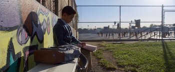 Movie still from “A Wrinkle in Time” (2018), directed by Ava DuVernay – A boy sitting on a park bench reading a book; Wide shot, High angle