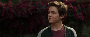 Movie still from “A Wrinkle in Time” (2018), directed by Ava DuVernay – A young man is standing in front of some flowers; Close Up shot, Over the shoulder angle