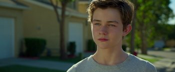 Movie still from “A Wrinkle in Time” (2018), directed by Ava DuVernay – A young man with blue eyes is standing in front of a house; Close Up shot, Over the shoulder angle