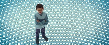 Movie still from “A Wrinkle in Time” (2018), directed by Ava DuVernay – A young boy standing in a room with white dots on the floor; Medium shot, Overhead angle