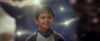 Movie still from “A Wrinkle in Time” (2018), directed by Ava DuVernay – A young boy smiling for the camera with the sun shining in the background; Close Up shot, Over the shoulder angle