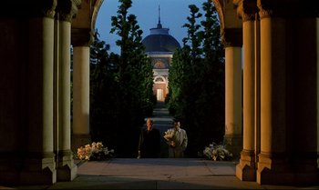 Movie still from “A Zed & Two Noughts” (1985), directed by Peter Greenaway – Two people standing in front of an archway at night; Extreme Wide shot, Low angle
