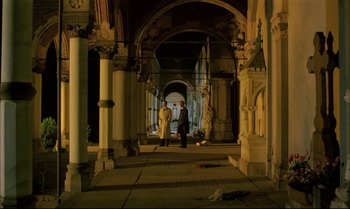 Movie still from “A Zed & Two Noughts” (1985), directed by Peter Greenaway – Two people are standing in an archway of a building; Extreme Wide shot, High angle