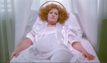 Movie still from “A Zed & Two Noughts” (1985), directed by Peter Greenaway – A woman in a white dress laying on a bed; Medium shot, Overhead angle