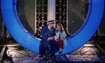 Movie still from “A Zed & Two Noughts” (1985), directed by Peter Greenaway – A man and a little girl are sitting on a bench; Wide shot, High angle