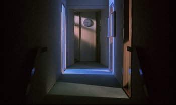 Movie still from “A Zed & Two Noughts” (1985), directed by Peter Greenaway – A hallway with a clock on the wall; Extreme Wide shot, High angle