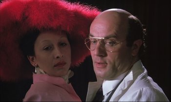 Movie still from “A Zed & Two Noughts” (1985), directed by Peter Greenaway – A man and a woman wearing a red hat and glasses; Close Up shot, Low angle