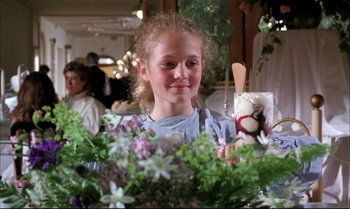 Movie still from “A Zed & Two Noughts” (1985), directed by Peter Greenaway – A young girl holding a wooden spoon in front of flowers; Close Up shot, Over the shoulder angle