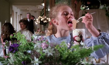 Movie still from “A Zed & Two Noughts” (1985), directed by Peter Greenaway – A little girl is eating some food at a restaurant; Medium shot, Low angle