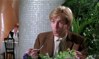 Movie still from “A Zed & Two Noughts” (1985), directed by Peter Greenaway – A man sitting at a table with a fork in his mouth; Close Up shot, Low angle