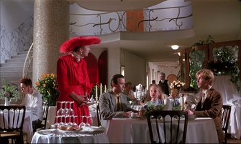 Movie still from “A Zed & Two Noughts” (1985), directed by Peter Greenaway – A group of people sitting at a table in a restaurant; Wide shot, Over the shoulder angle
