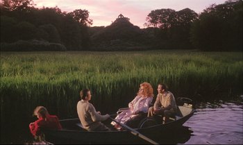 Movie still from “A Zed & Two Noughts” (1985), directed by Peter Greenaway – A group of people sitting in a boat on a river; Extreme Wide shot, High angle