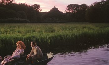 Movie still from “A Zed & Two Noughts” (1985), directed by Peter Greenaway – Two people are sitting on a boat in the water; Extreme Wide shot, High angle