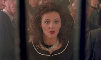 Movie still from “A Zed & Two Noughts” (1985), directed by Peter Greenaway – A person with curly hair wearing a necklace; Close Up shot, Over the shoulder angle