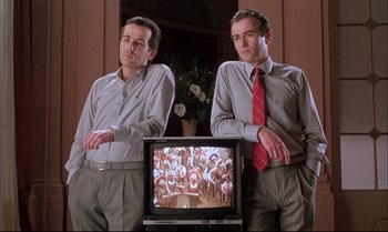 Movie still from “A Zed & Two Noughts” (1985), directed by Peter Greenaway – A couple of men standing in front of a television; Medium shot, Low angle