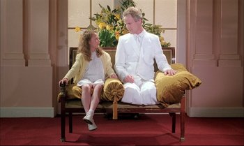 Movie still from “A Zed & Two Noughts” (1985), directed by Peter Greenaway – A man and a woman sitting on a couch; Wide shot, Low angle