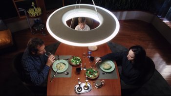 Movie still from “A.I. Artificial Intelligence” (2001), directed by Steven Spielberg – Two people sitting at a table with a child eating salad; Wide shot, Overhead angle