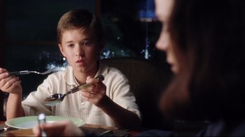 Movie still from “A.I. Artificial Intelligence” (2001), directed by Steven Spielberg – A young boy sitting at a table with a fork in his mouth; Close Up shot, Over the shoulder angle