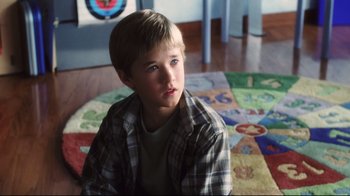 Movie still from “A.I. Artificial Intelligence” (2001), directed by Steven Spielberg – A young boy sitting on the floor in front of a rug; Close Up shot, High angle