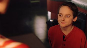 Movie still from “A.I. Artificial Intelligence” (2001), directed by Steven Spielberg – A boy in a red shirt is smiling for the camera; Close Up shot, High angle