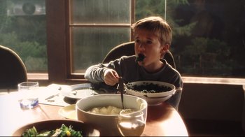 Movie still from “A.I. Artificial Intelligence” (2001), directed by Steven Spielberg – A young boy sitting at a table with a bowl of mashed potatoes; Medium shot, High angle