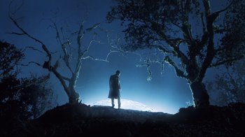 Movie still from “A.I. Artificial Intelligence” (2001), directed by Steven Spielberg – A man standing on top of a hill near some trees; Extreme Wide shot, Low angle