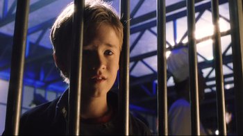 Movie still from “A.I. Artificial Intelligence” (2001), directed by Steven Spielberg – A young boy standing behind a metal fence; Close Up shot, Low angle
