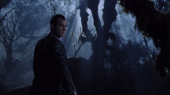 Movie still from “A.I. Artificial Intelligence” (2001), directed by Steven Spielberg – A man standing next to a tree in the dark; Medium shot, Low angle