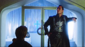 Movie still from “A.I. Artificial Intelligence” (2001), directed by Steven Spielberg – A man in a black outfit standing in front of a door; Medium shot, Low angle