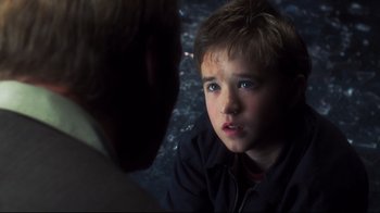 Movie still from “A.I. Artificial Intelligence” (2001), directed by Steven Spielberg – A young boy looking at another young man in a dark room; Close Up shot, Over the shoulder angle