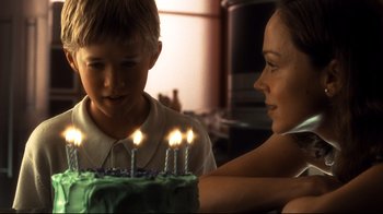 Movie still from “A.I. Artificial Intelligence” (2001), directed by Steven Spielberg – A woman and a boy looking at a birthday cake with lit candles on it; Close Up shot, Over the shoulder angle