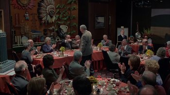 Movie still from “About Schmidt” (2002), directed by Alexander Payne – A group of people sitting around a table with food; Wide shot, High angle