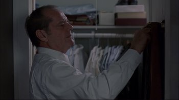 Movie still from “About Schmidt” (2002), directed by Alexander Payne – A man in a white dress shirt is looking at clothes on hangers in a closet; Medium shot, Over the shoulder angle