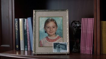 Movie still from “About Schmidt” (2002), directed by Alexander Payne – A picture of a young girl in a picture frame on top of a bookshelf; Close Up shot, High angle