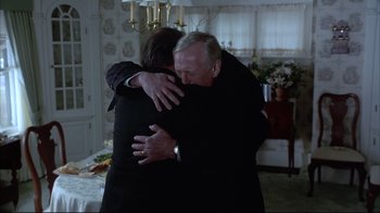 Movie still from “About Schmidt” (2002), directed by Alexander Payne – A man and a woman hugging in a living room; Medium shot, Over the shoulder angle