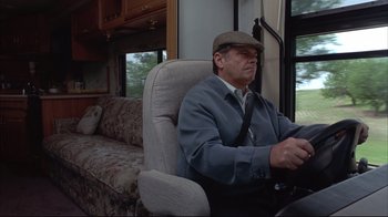 Movie still from “About Schmidt” (2002), directed by Alexander Payne – An older man sitting in a chair in a living room next to a couch; Medium shot, Low angle