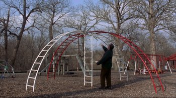 Movie still from “About Schmidt” (2002), directed by Alexander Payne – A man standing next to a red and white structure; Extreme Wide shot, Low angle