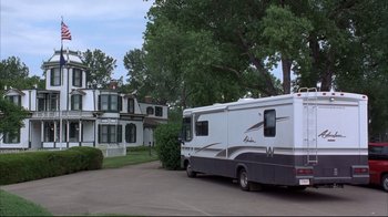 A motorhome is parked in a driveway near a house