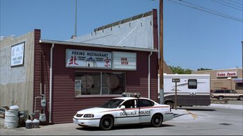 Movie still from “About Schmidt” (2002), directed by Alexander Payne – A police car parked in front of a restaurant; Extreme Wide shot, Low angle