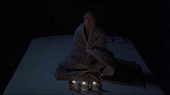 Movie still from “About Schmidt” (2002), directed by Alexander Payne – A man wrapped in a blanket sitting on top of a skateboard; Wide shot, High angle