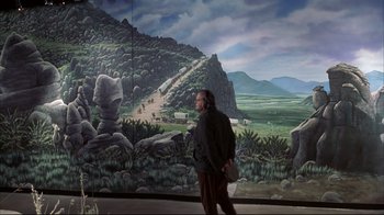 Movie still from “About Schmidt” (2002), directed by Alexander Payne – A man walking in front of a painting of a mountain; Extreme Wide shot, Over the shoulder angle