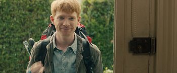 Movie still from “About Time” (2013), directed by Richard Curtis – A man with a backpack standing in front of a window; Close Up shot, Over the shoulder angle