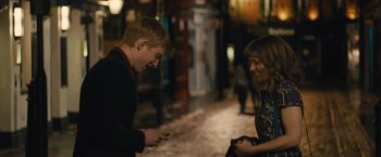 Movie still from “About Time” (2013), directed by Richard Curtis – A man and a woman looking at a cell phone on the sidewalk; Medium shot, Over the shoulder angle