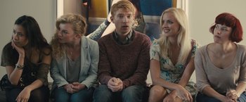 Movie still from “About Time” (2013), directed by Richard Curtis – A man sitting next to two other women; Medium shot, Over the shoulder angle