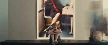 Movie still from “About Time” (2013), directed by Richard Curtis – A boy sitting on the ground in front of a picture of a woman; Medium shot, High angle