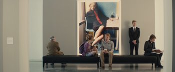 Movie still from “About Time” (2013), directed by Richard Curtis – Two people sitting in front of a large poster of a woman; Wide shot, Over the shoulder angle